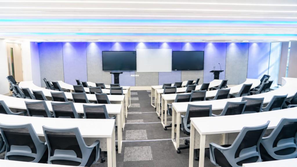 Tiered lecture hall with twin display screens and ambient lighting