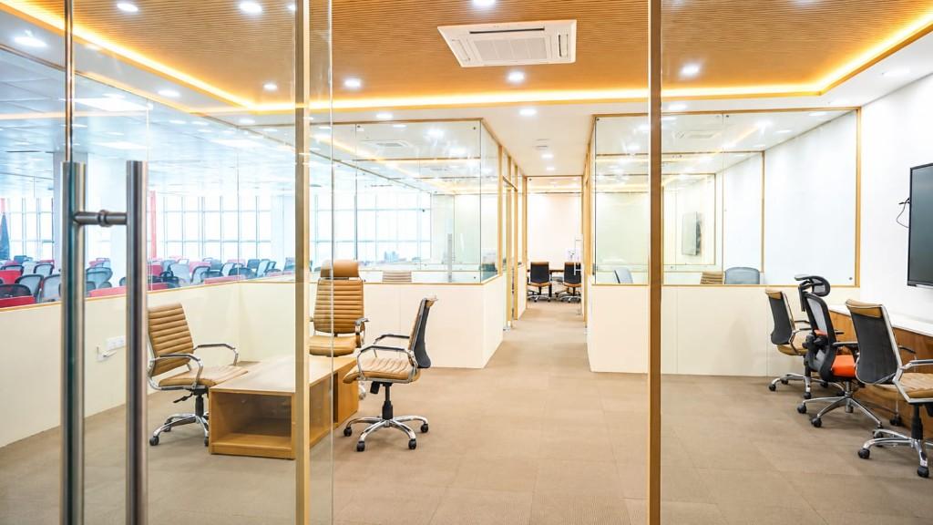 Glass-walled collaborative workspace with private cabins and shared desks